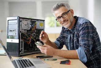 Ein Mann neben einem Computer lächelt 